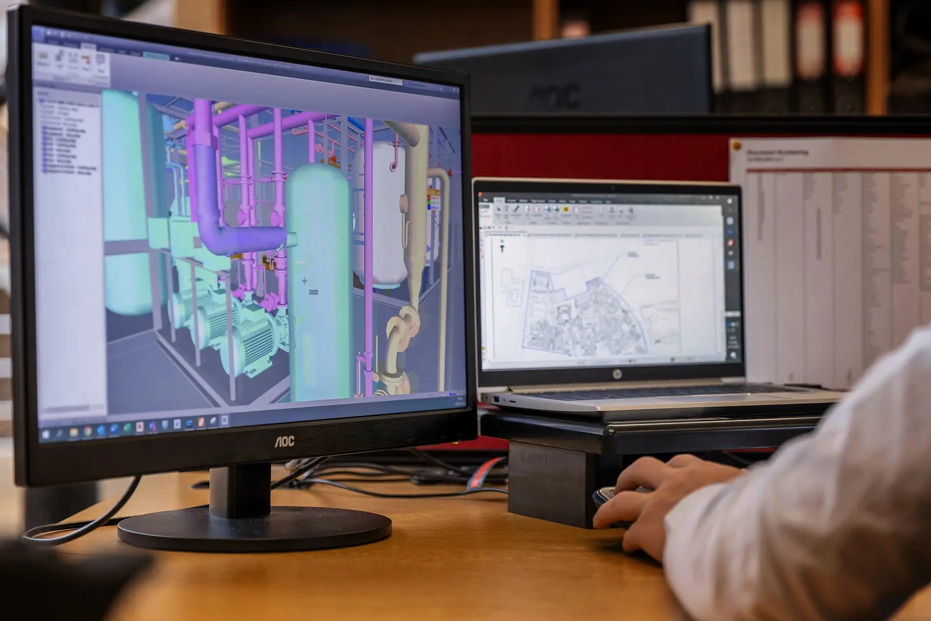 En person arbetar med 3D-modellering av ett industrisystem på en datorskärm